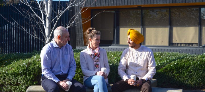 Mental health nurse sitting on a bench outside having coffee with two clients