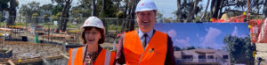 Two people wearing high vis jackets and hardhats over business wear